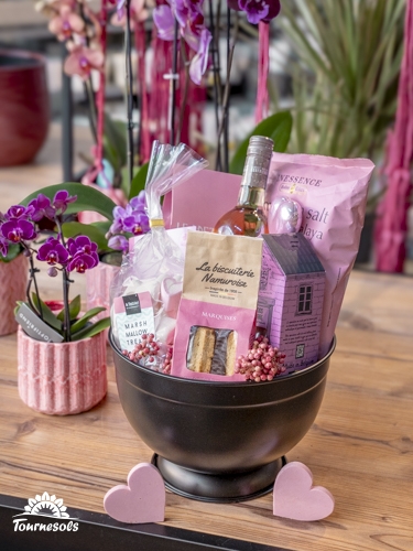 Panier garni gourmand rose avec douceurs sucrées, biscuiterie et boisson, idéal cadeau de Saint-Valentin.